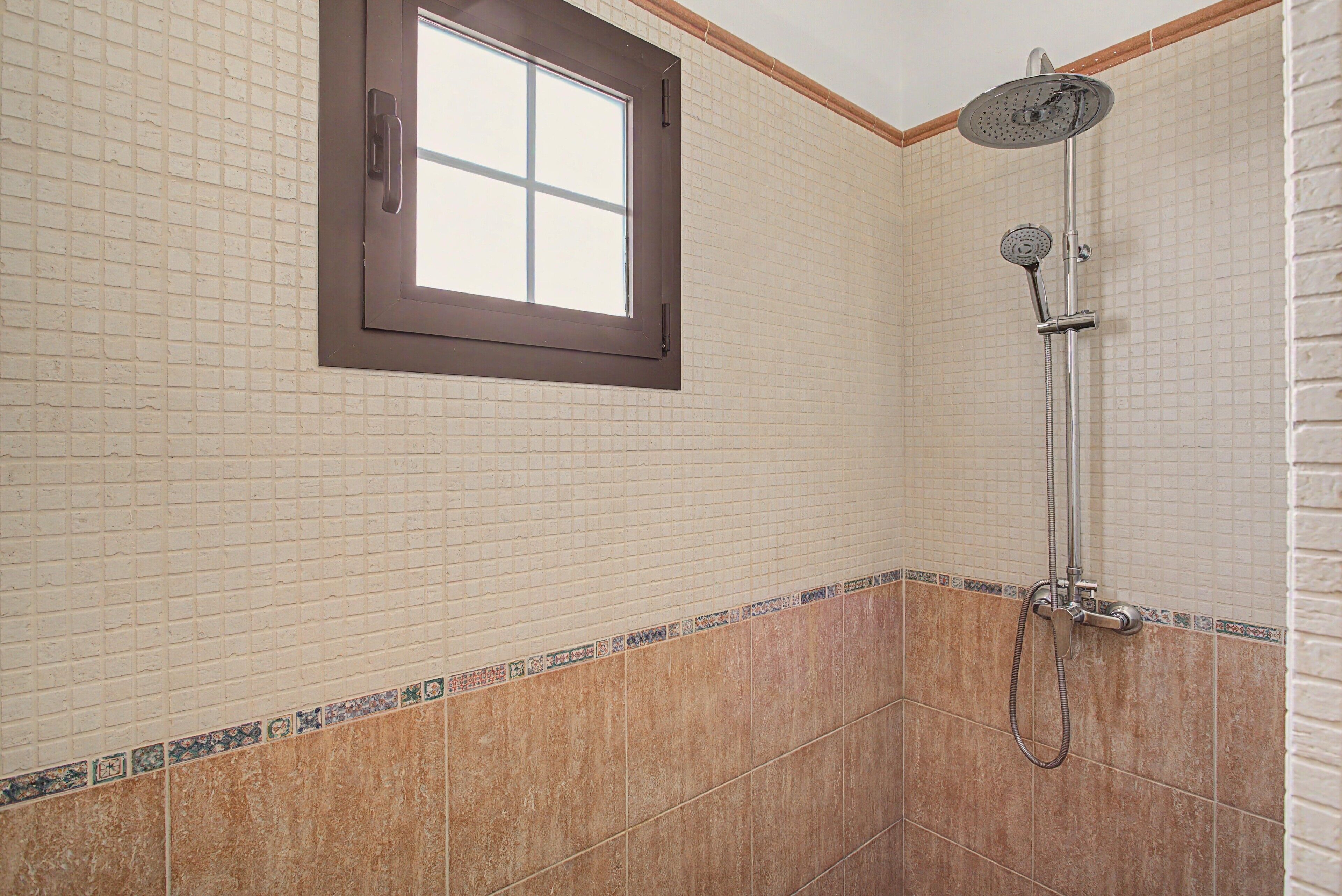 A bathroom with a shower, a window, and tiled walls.