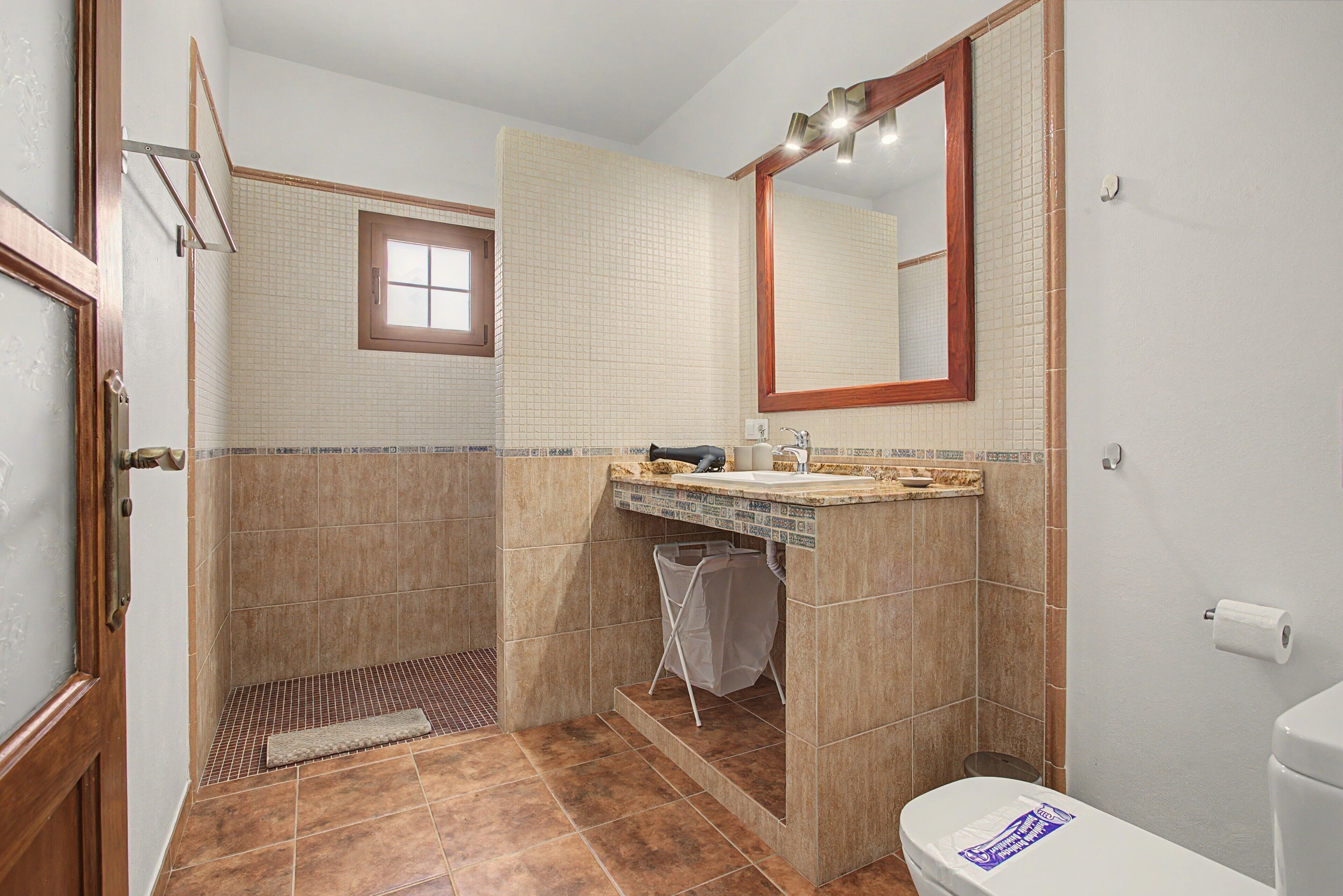 Une salle de bain avec une douche, un lavabo, des toilettes et une fenêtre.