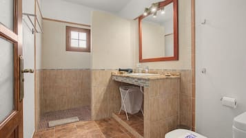 Une salle de bain avec une douche, un lavabo, des toilettes et une fenêtre.