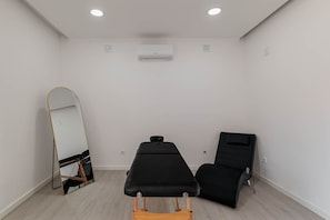 A room with a large mirror, two black chairs, a wooden bench, and an air conditioning unit on the wall. - Room 'Suite King 1' with Mountain View, Shared Pool and Wi-Fi (Alviobeira)