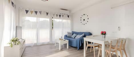 A modern living space with a dining area, a sofa, and a kitchen area.
