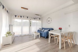 A modern living space with a dining area, a sofa, and a kitchen area.