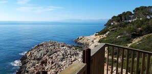 A coastal view with rocky terrain and a wooden railing.