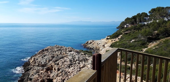 A coastal view with rocky terrain and a wooden railing.