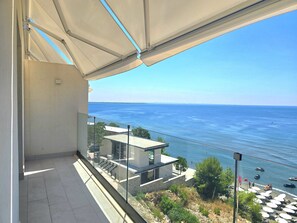 A balcony with a view of the sea, a modern building, and a beach with umbrellas. - Panorama Deep Blue 001 (Shengjin)
