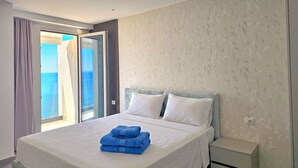 Quarto de hotel com uma cama, uma mesa de cabeceira e vista para o mar pela janela.