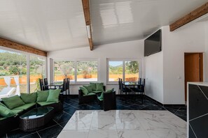 A spacious room with a large window, a flat-screen TV, and a dining area with chairs and a table. - Spa Local Accommodation Tomar (Alviobeira)