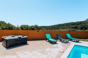 A rooftop pool area with a hot tub and lounge chairs.