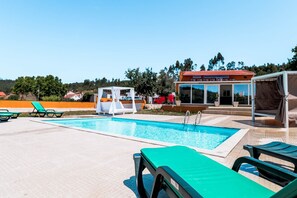 A swimming pool with lounge chairs, a cabana, and a building with large windows. - Spa Local Accommodation Tomar (Alviobeira)