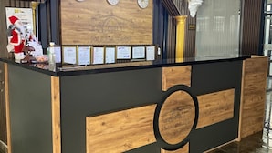 Um balcão de recepção com design em madeira e preto, com um relógio, certificados emoldurados e uma decoração de Papai Noel.