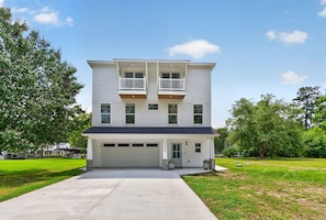 A two-story residential building with a garage, a covered driveway, and a well-maintained lawn.
