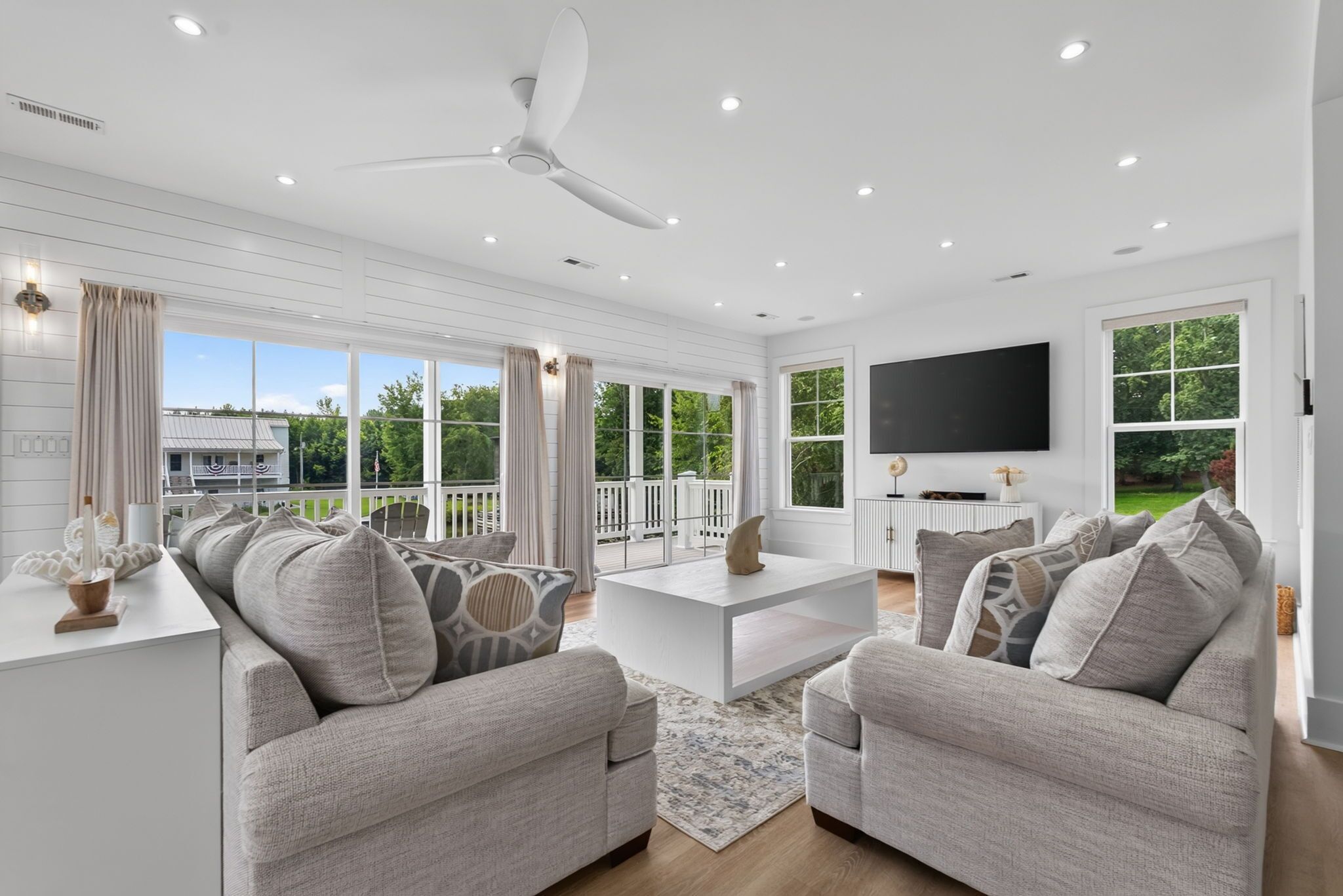 A modern living room with a large TV, comfortable seating, and a view of the outdoors.