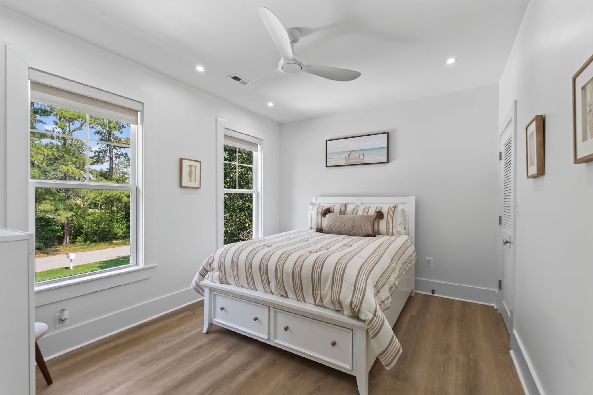 A bedroom with a bed, a ceiling fan, a window, and a door.