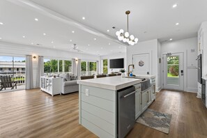 A modern kitchen with a central island, built-in appliances, and a large window overlooking a deck.
