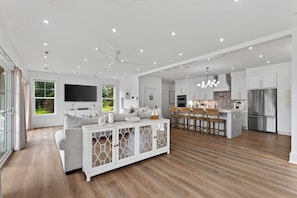 A modern kitchen with white cabinetry, a stainless steel refrigerator, and a bar area with stools.