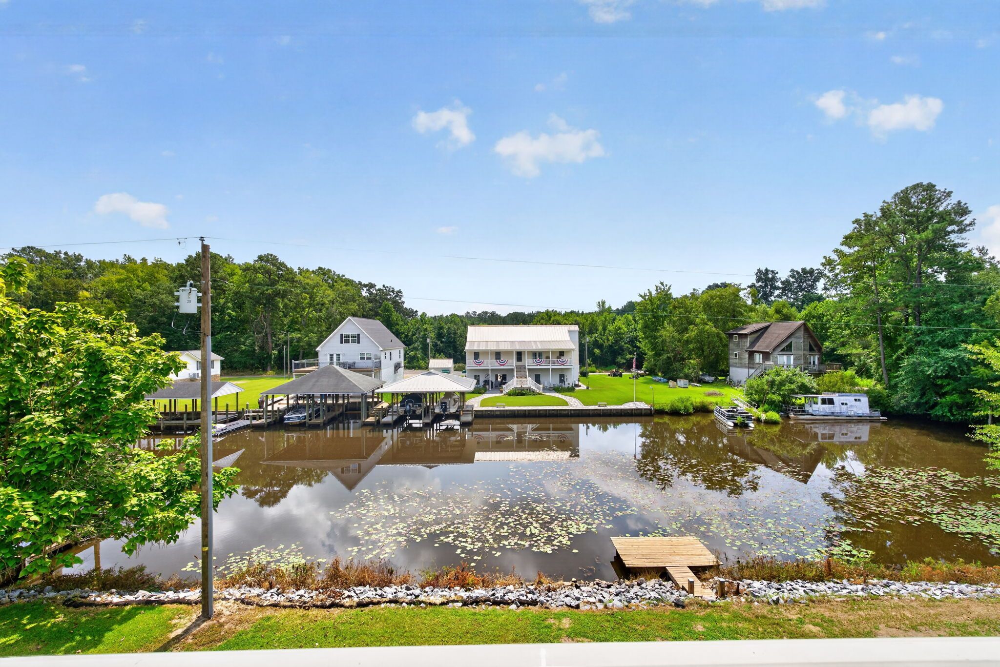 A lakeside property with a dock, a white building with a porch, and a smaller cabin.