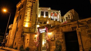 A historic building with a stone facade, a prominent entrance with a sign, and a staircase leading to an upper level. - La Mar Cave Cappadocia (Ürgüp)