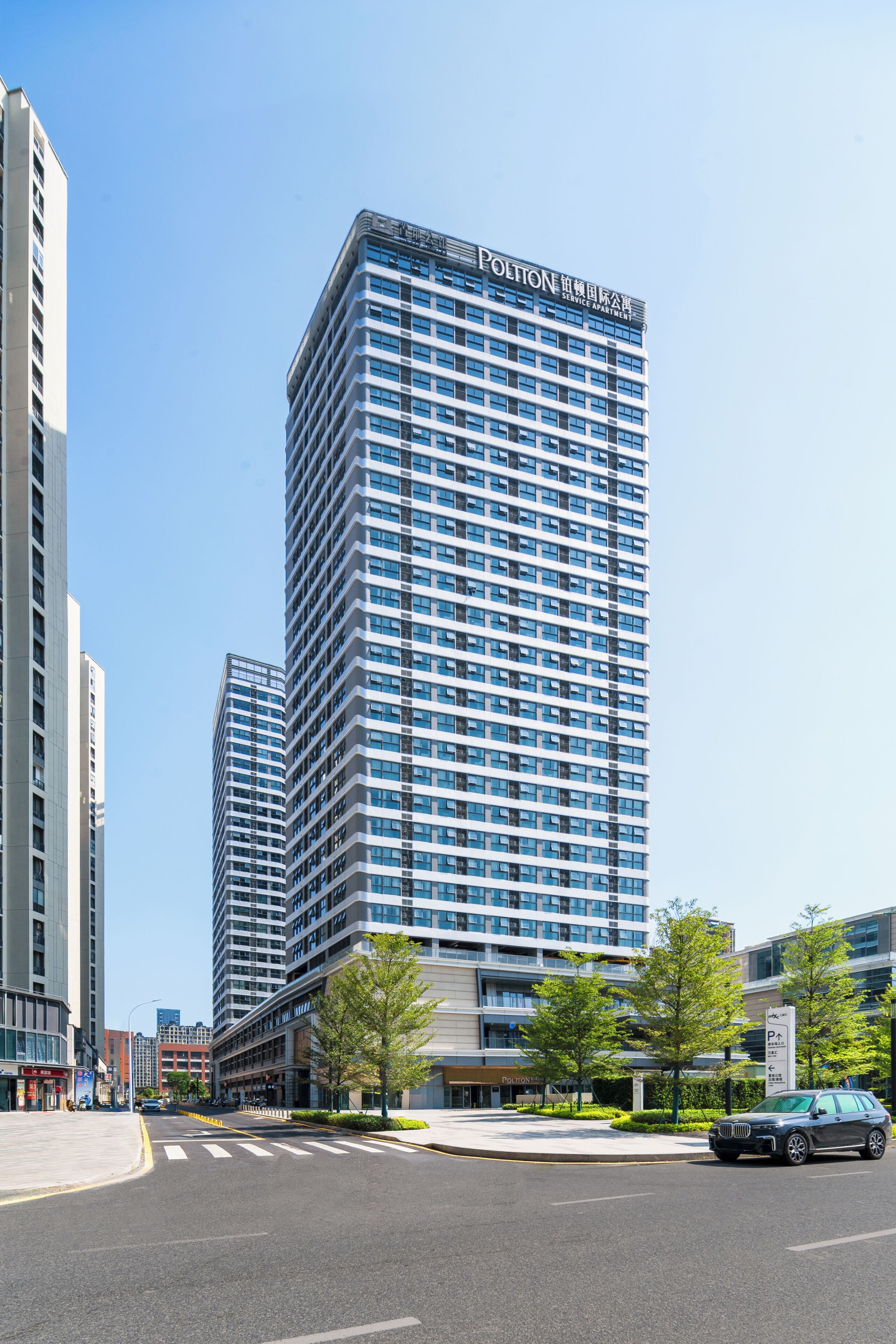 Um edifício alto com apartamentos de serviço, apresentando um design arquitetônico moderno com uma grade de janelas e uma sinalização proeminente no topo.
