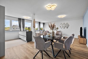 Un comedor moderno con una mesa de vidrio, sillas tapizadas en gris y un jarrón decorativo.