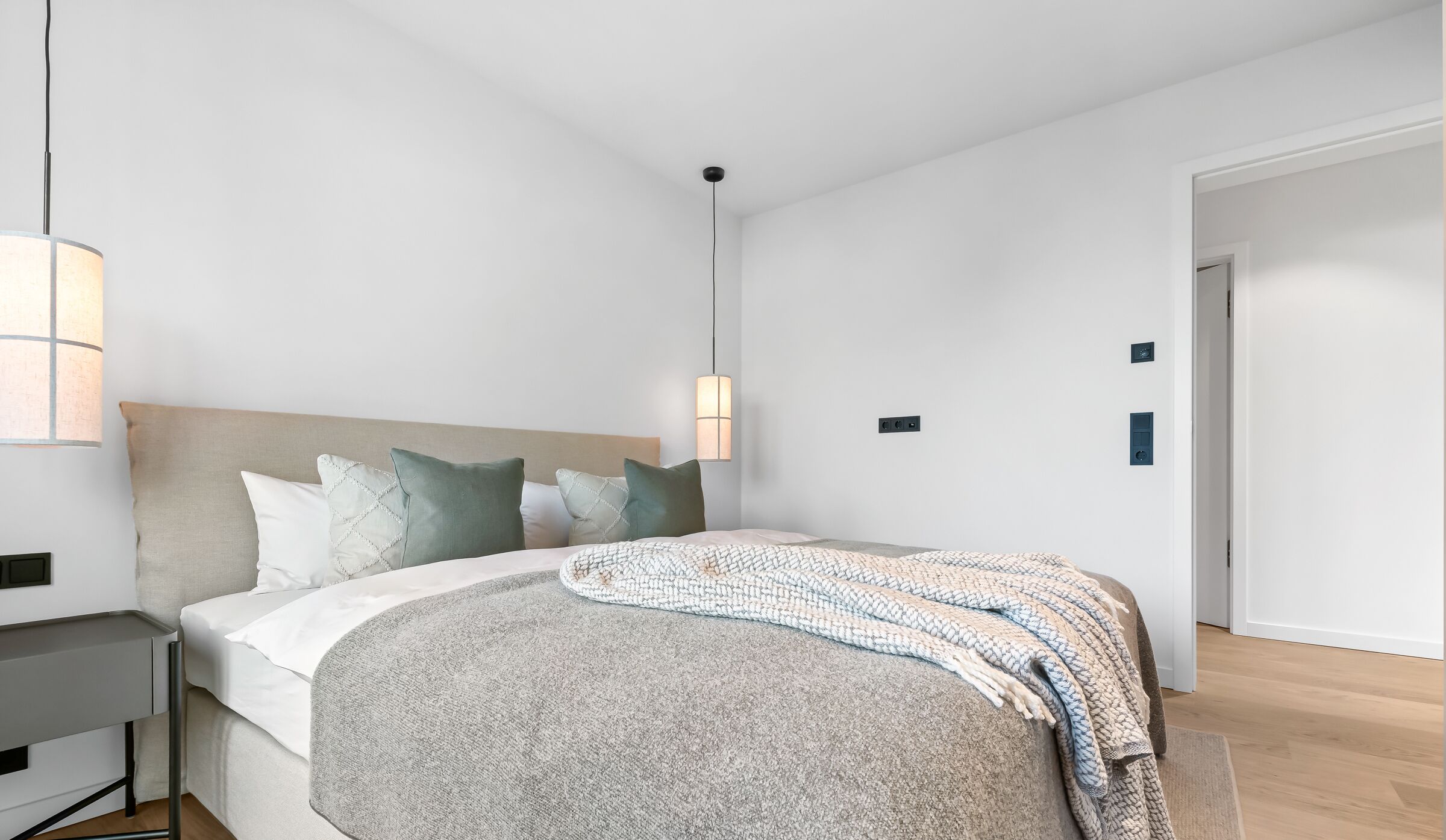 Een moderne slaapkamer met een bed, nachtkastjes en een hanglamp.