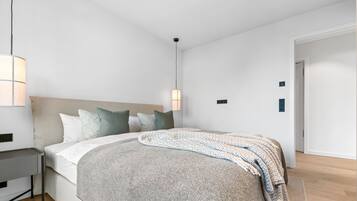 Een moderne slaapkamer met een bed, nachtkastjes en een hanglamp.