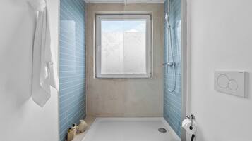 Ein modernes Badezimmer mit Dusche, Toilette und Fenster.