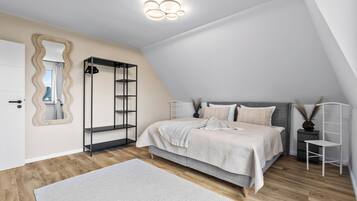 Ein Schlafzimmer mit Bett, Kleiderschrank, Spiegel und einer Deckenleuchte.