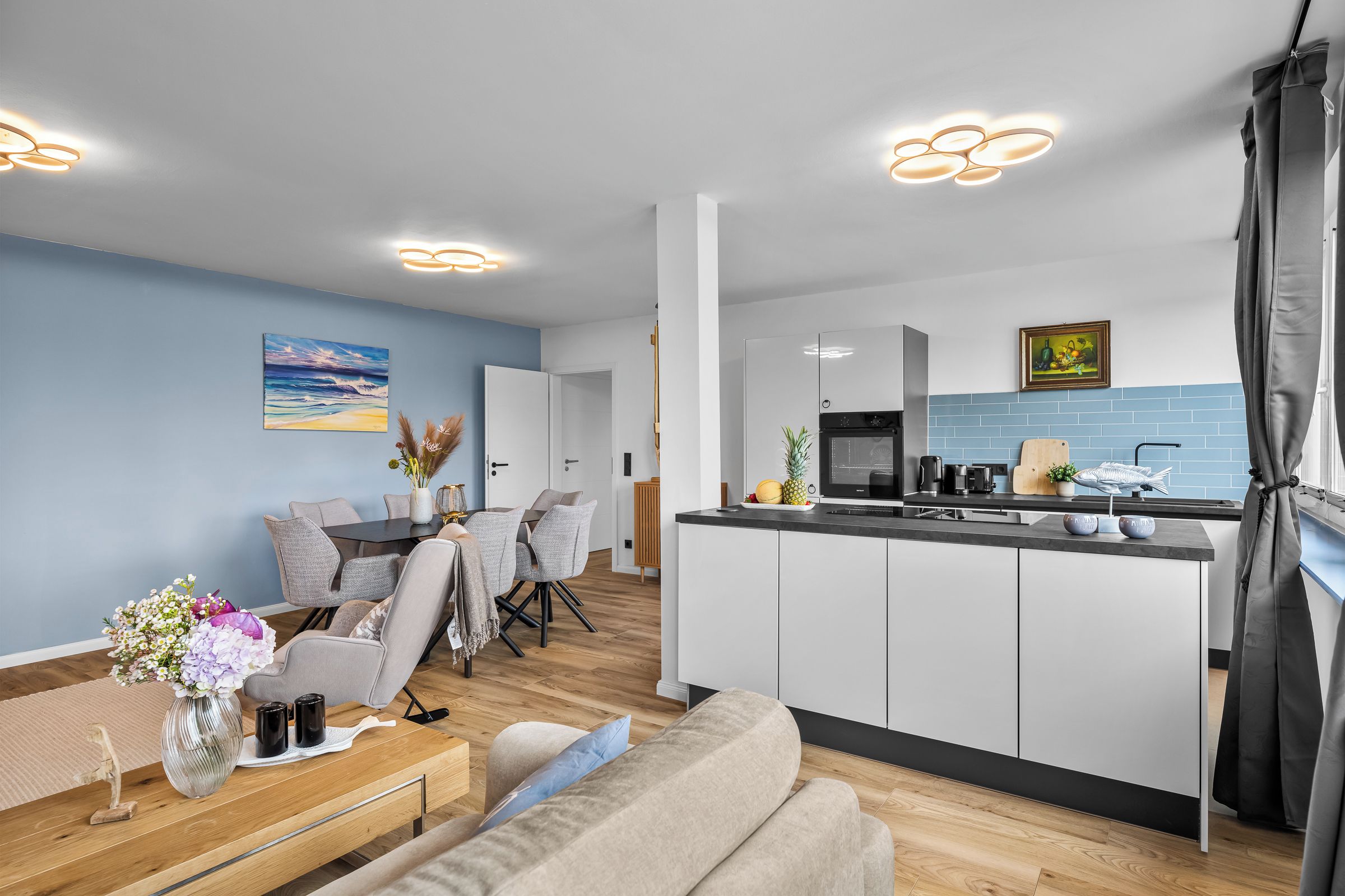 Ein modernes Wohnzimmer mit Essbereich, Küche und Blick ins Freie.