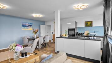 Ein modernes Wohnzimmer mit Essbereich, Küche und Blick ins Freie.