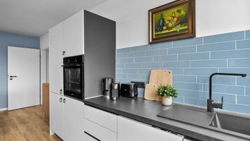 Eine moderne Küche mit weißen Schränken, einer schwarzen Arbeitsplatte, einer Kaffeemaschine, einem Toaster und einem Holzschneidebrett.