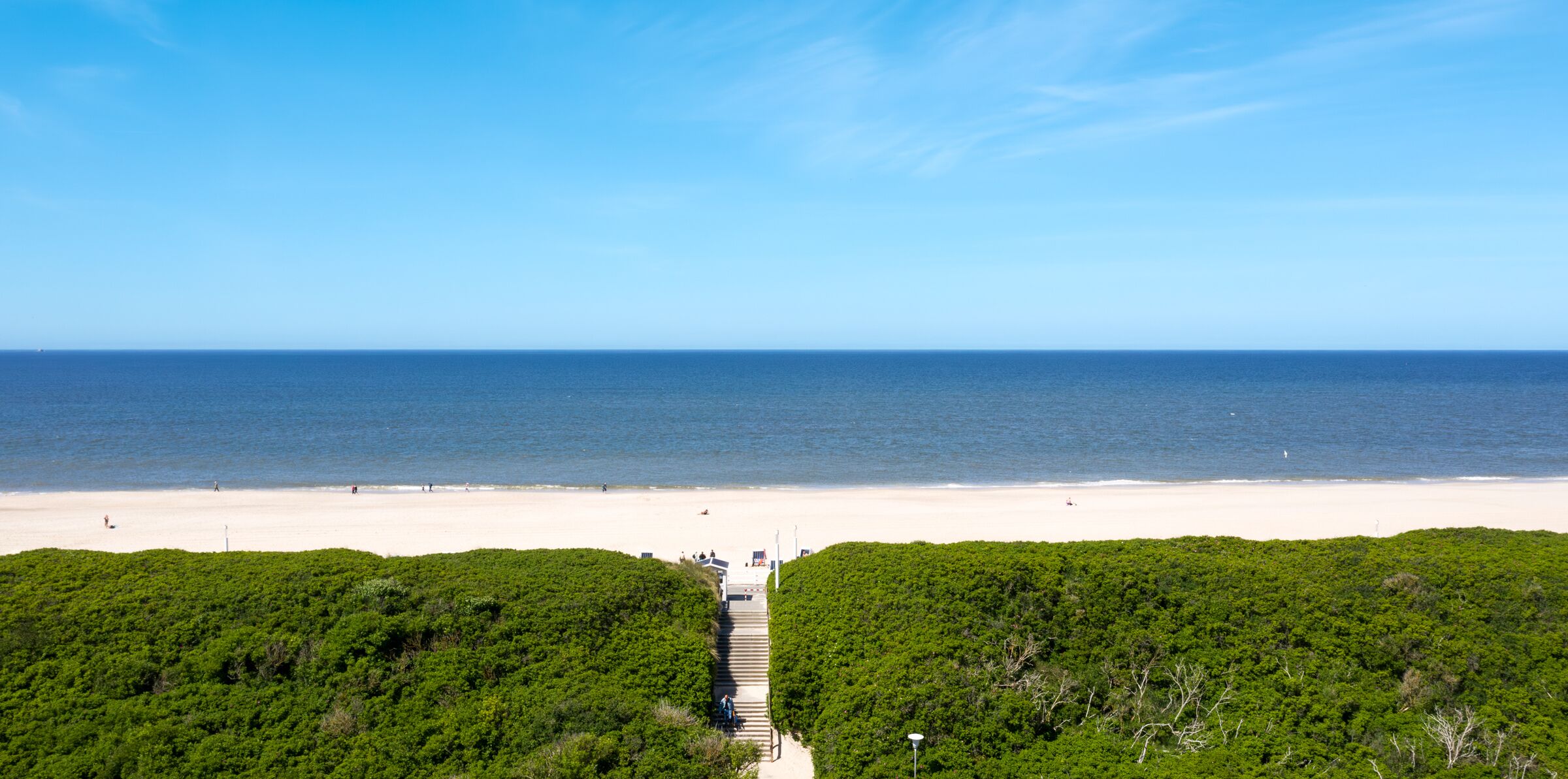 Een strand met een heldere lucht, een zandstrand en een pad dat naar het strand leidt.