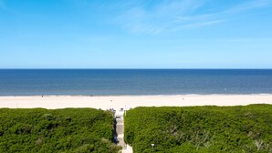 Une plage avec un ciel dégagé, un rivage sablonneux et un sentier menant à la plage.