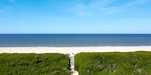 Une plage avec un ciel dégagé, un rivage sablonneux et un sentier menant à la plage.
