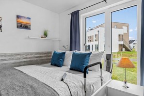 Een moderne slaapkamer met een groot bed, een nachtkastje, een lamp en uitzicht op het exterieur.
