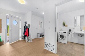 A modern, well-lit laundry room with a Bosch washing machine, a sink, and a mirror. - Rolli-Oase - wheelchair-accessible, kitchen with space for a wheelchair, infrared sauna, close to the beach (Olpenitz)