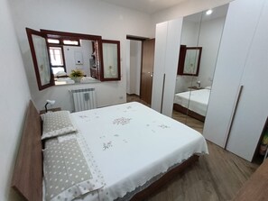 Een slaapkamer met een bed, een dressoir, een spiegel en een kledingkast.