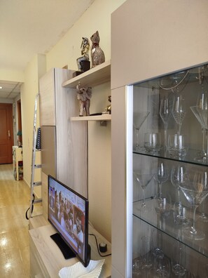 Ein Zimmer mit Fernseher auf einem Holzboden, einer Leiter und einem Regal mit Dekorationsobjekten.