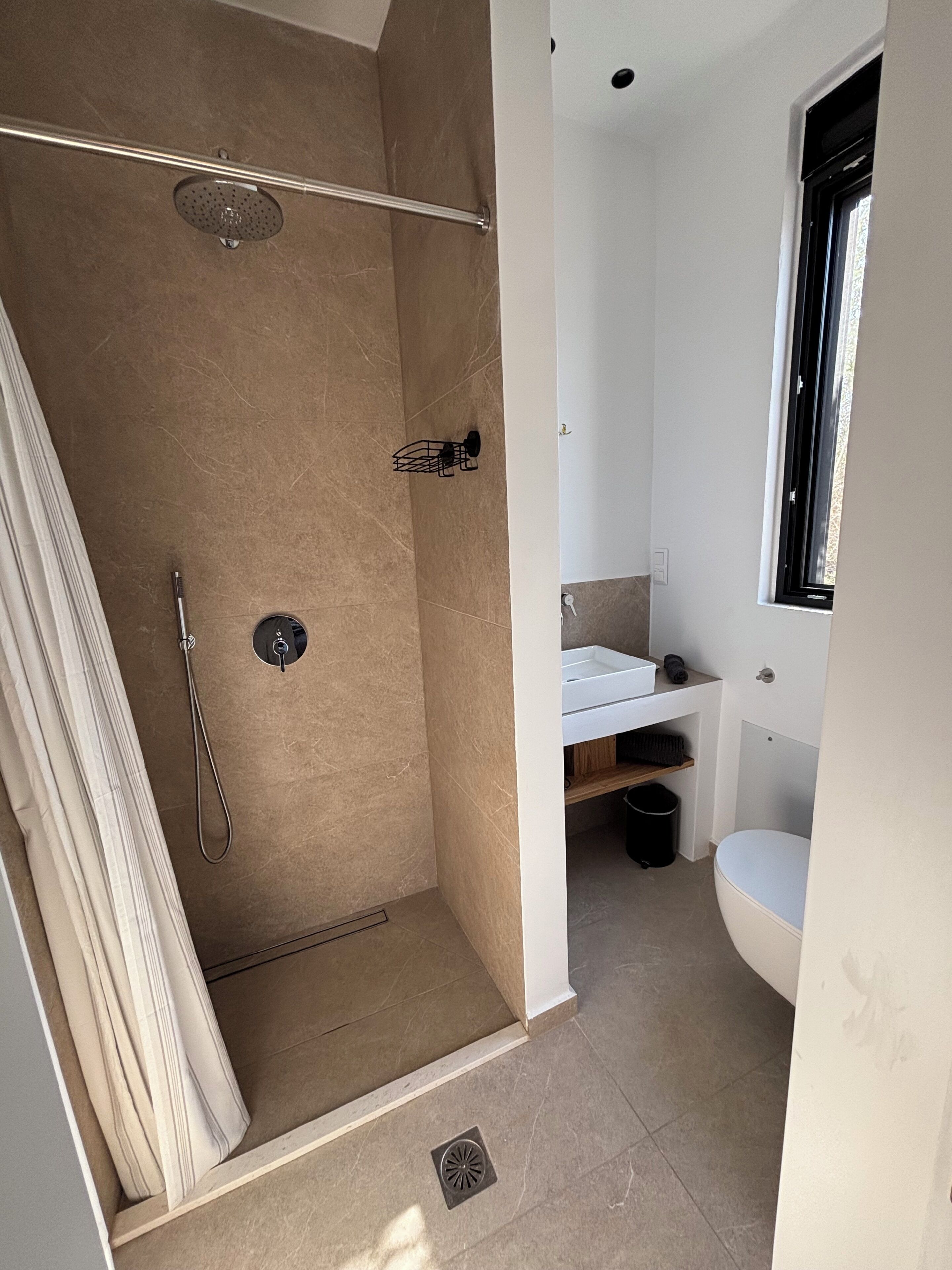 Un baño con ducha, inodoro, lavabo y ventana.
