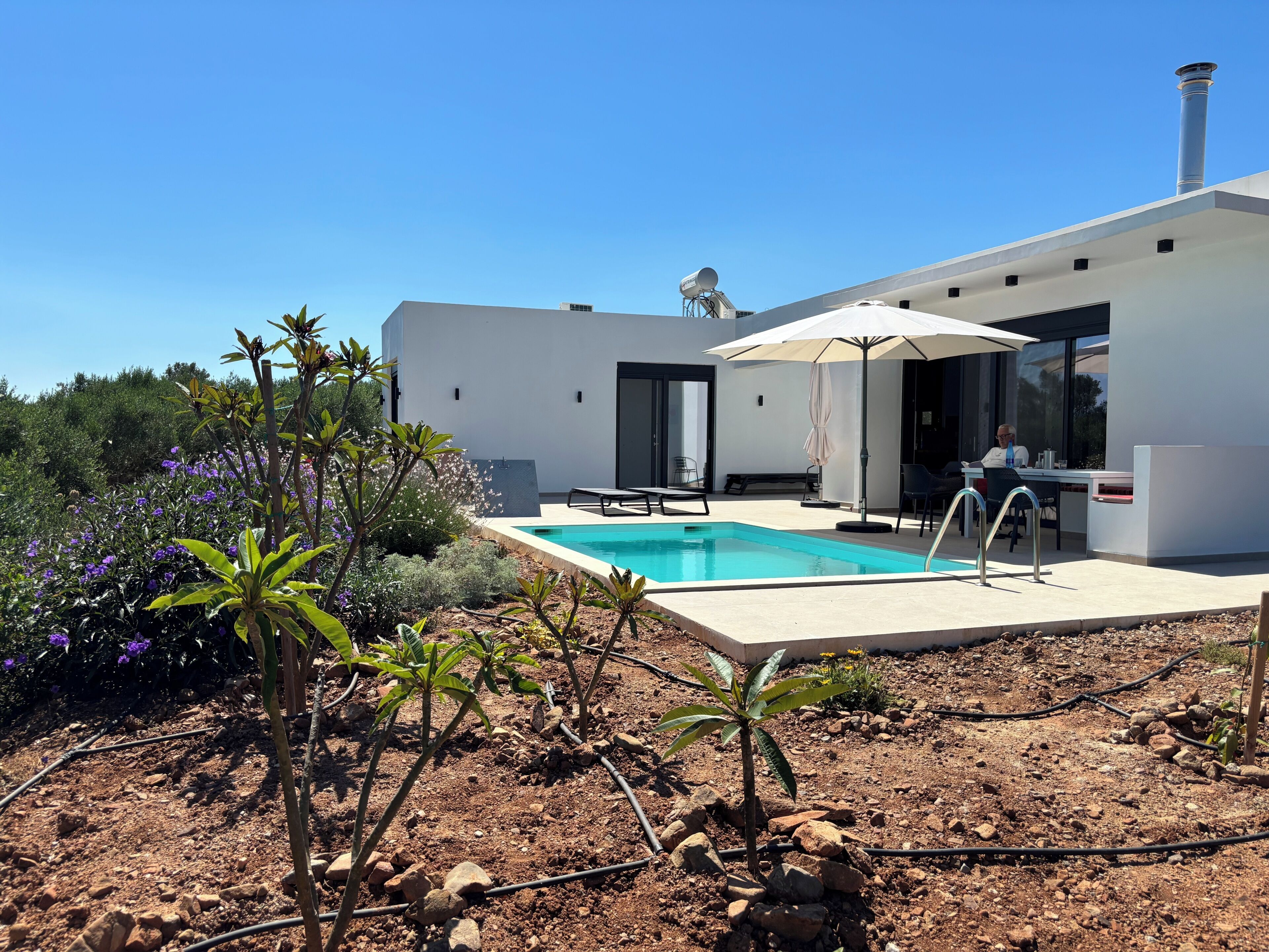 A modern house with a swimming pool, outdoor seating, and a garden.