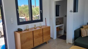 Une pièce avec un meuble en bois, une fenêtre, une porte et un canapé vert.