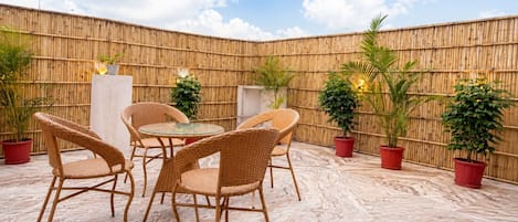 An outdoor patio area with wicker furniture and potted plants.