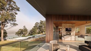 Uma sala de estar moderna com lareira de pedra, televisão e vista para a água.