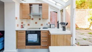 A modern kitchen with a built-in oven, a toaster, and a window overlooking a brick wall. - Lovely Garden Flat in Kentish Town (Greater London)