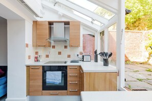 Eine moderne Küche mit Einbauofen, Toaster und Fenster mit Blick auf eine Backsteinmauer.