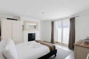Une chambre d’hôtel avec un lit, une cheminée, une armoire, un miroir et une vue sur l’extérieur.