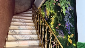 A marble staircase with ornate golden railings and a wall adorned with artificial greenery and flowers. - Vista Villa Premium Apartment | Copacabana (Rio de Janeiro)