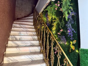 A marble staircase with ornate golden railings and a wall adorned with artificial greenery and flowers. - Vista Villa Premium Apartment | Copacabana (Rio de Janeiro)