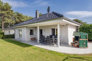 A single-story house with a covered patio, a chimney, and a satellite dish. - Family-friendly vacation rental with a garden and a fireplace (Karlshagen)