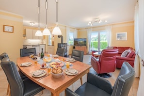 A modern living space with a dining area, kitchen, and a red leather sofa. - Family-friendly vacation rental with a garden and a fireplace (Karlshagen)