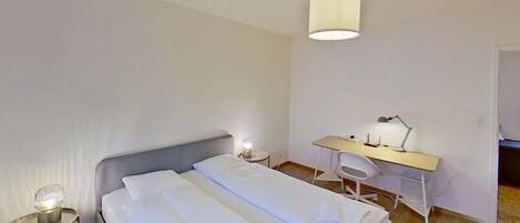 A hotel room with a bed, a desk, and a chair.